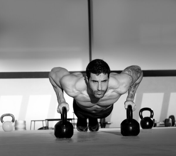 Gym man push-up strength pushup with Kettlebell