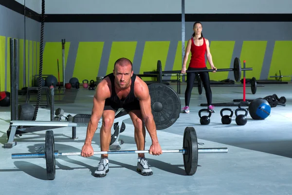 Gimnasio con barra de levantamiento de pesas entrenamiento hombre y mujer —  Fotos de Stock