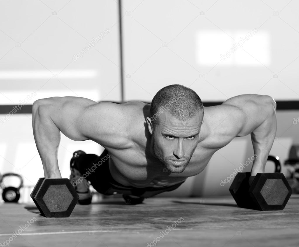 Gym man push-up strength pushup with dumbbell