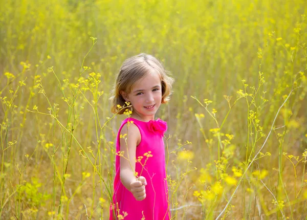 Criança menina na primavera flores amarelas campo e vestido rosa — Fotografia de Stock