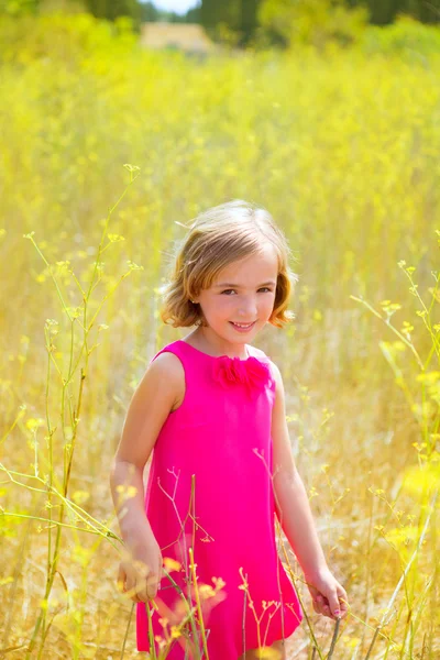 Niña niña niña en primavera flores amarillas campo y vestido rosa —  Fotos de Stock