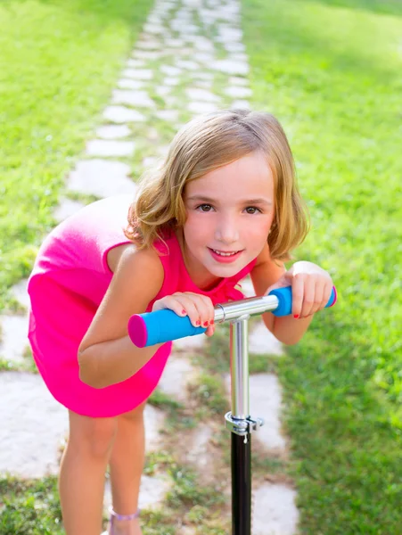 Niño feliz niña jugando con scooter en el jardín — Foto de Stock