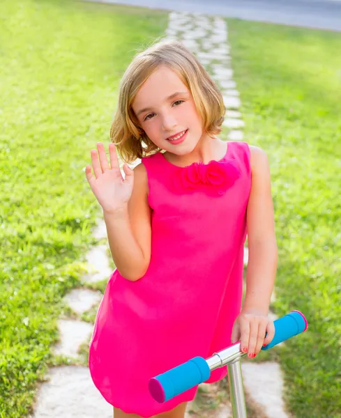 Gelukkig meisje kind spelen met scooter in tuin — Stockfoto