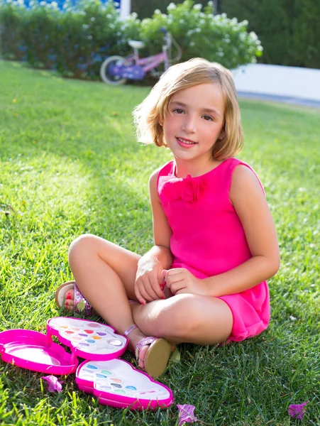 Bambina bambina che gioca con il trucco set seduto in erba — Foto Stock