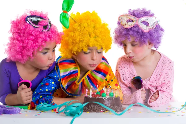 Bambini festa di compleanno clown parrucche soffiando candele torta — Foto Stock