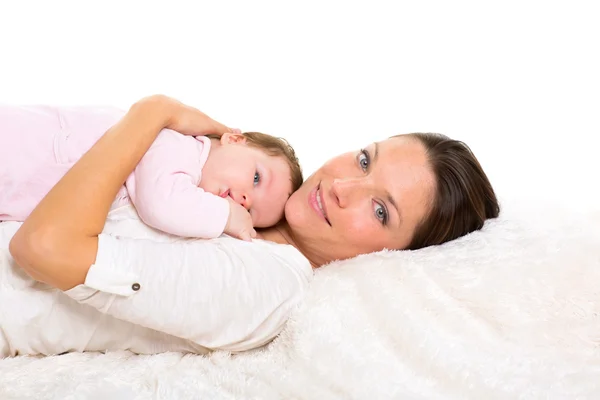 Baby flicka och mamma liggande glada tillsammans på vit päls — Stockfoto