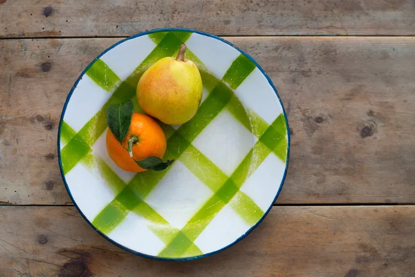 Фрукти мандарин і груша в старовинній порцеляновій тарілці — стокове фото