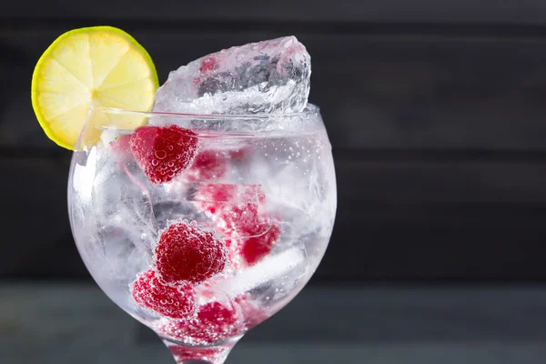 Cóctel de gin tonic con frambuesa y macro hielo de cerca —  Fotos de Stock