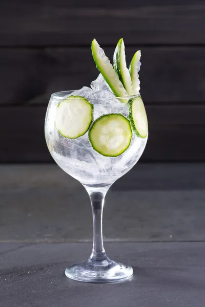 Gin tonic cocktail with cucumber and ice on black — Stock Photo, Image