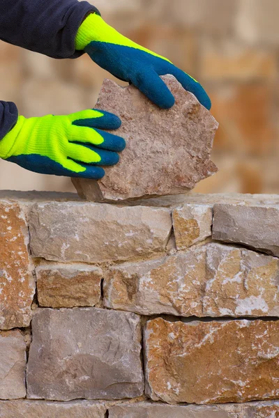 Mason mãos trabalhando na parede de pedra de alvenaria — Fotografia de Stock