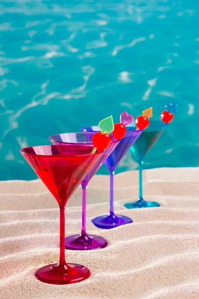 Bunter Cocktail in einer Reihe mit Kirsche am tropischen Sandstrand — Stockfoto