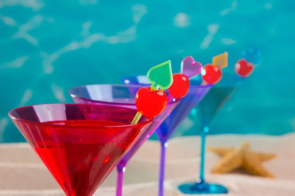 Cocktail coloré dans une rangée avec cerise sur la plage de sable tropical — Photo