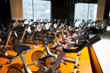 Aerobics spinning exercise bikes gym room in a row