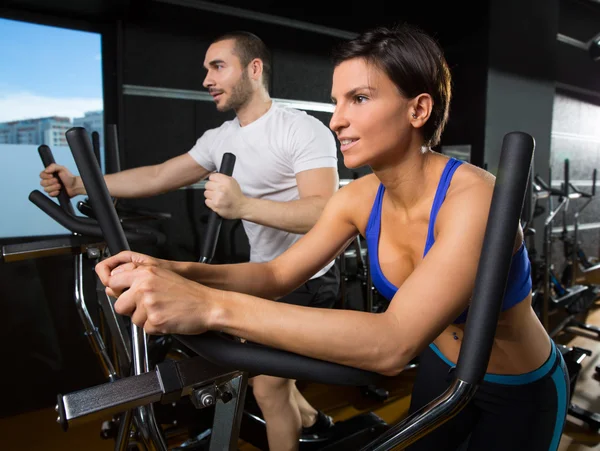 Elliptical walker trainer man and woman at black gym — Stockfoto