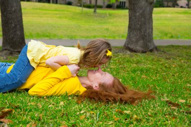park çim üzerinde yalan oynayan anne ve kızı