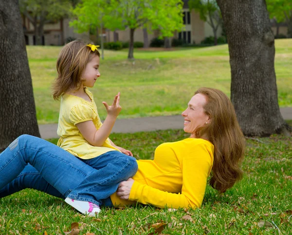 Hija y madre jugando a contar tumbado en el césped — Foto de Stock