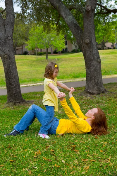 Daughter and mother playing lying on park lawn — Stock Photo, Image