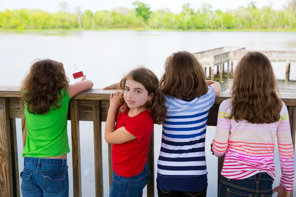 Crianças meninas de volta olhando para o lago no corrimão — Fotografia de Stock