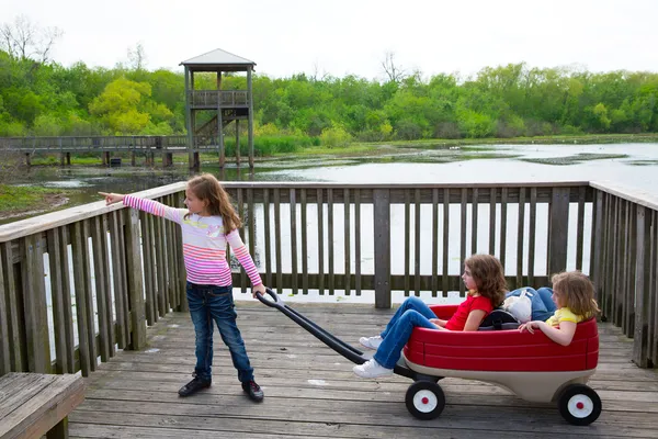 Flickor söker på park sjön med utomhus dump cart — Stockfoto