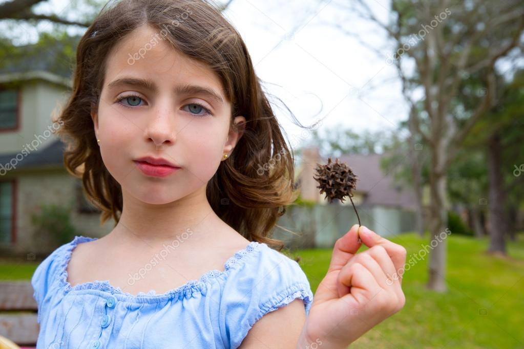 girl portrait with sweetgum spiked fruit on park