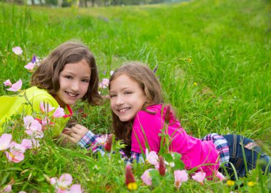 happy twin sister girls playing on spring flowers meadow clipart