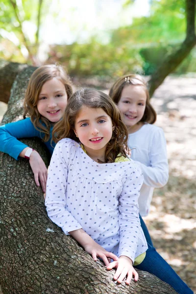 Amigo hermanas niñas descansando en árbol tronco naturaleza — Foto de Stock