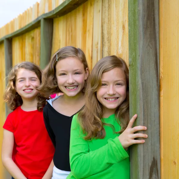 Grils grupp i rad leende i ett staket i trä — Stockfoto