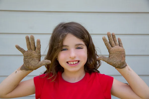 幸せな子供の少女に笑みを浮かべて、汚れた手で泥で遊んで — ストック写真