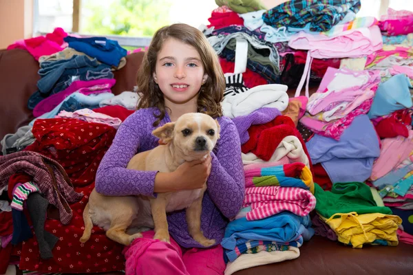 Chica sentada en un sofá de ropa desordenado con perro chihuahua —  Fotos de Stock