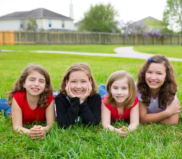 Children girls group lying on lawn grass smiling happy — Stock Photo, Image
