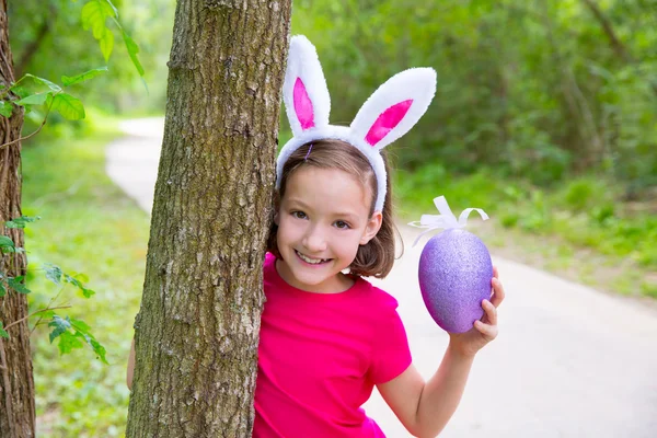 Menina de Páscoa com grande ovo roxo e orelhas de coelho engraçado — Fotografia de Stock