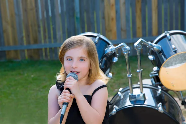 Blondes Mädchen singt im Hinterhof mit Trommeln — Stockfoto