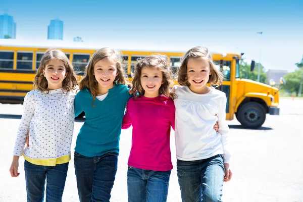 Écolières amis dans une rangée à pied de bus scolaire — Photo