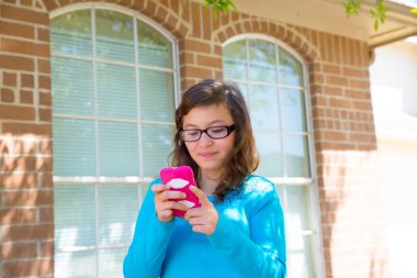 Teenager girl with glasses playing with smartphone clipart