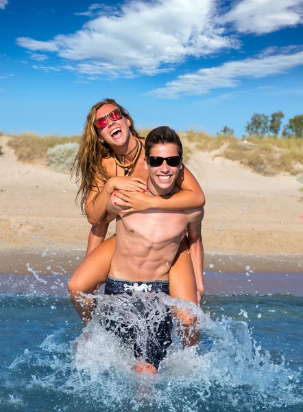 Adolescente pareja disfrutando piggyback en verano playa —  Fotos de Stock