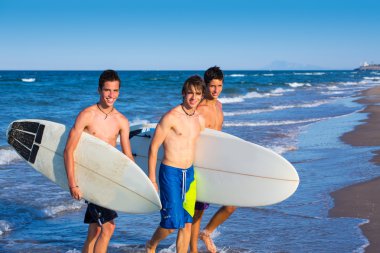 Boys surfers group coming out from beach