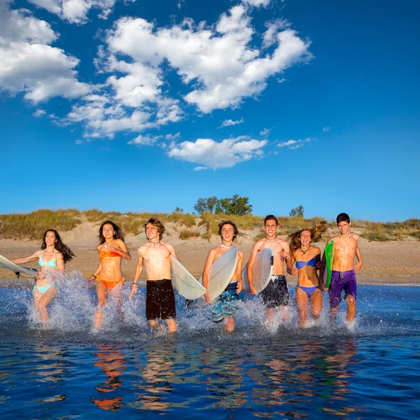 Adolescentes surfistas grupo corriendo playa splashing —  Fotos de Stock