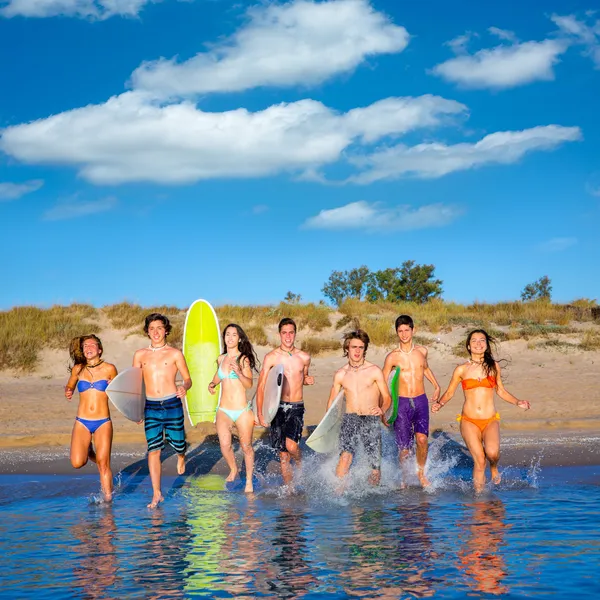 Teenager surfisti gruppo corsa spiaggia schizzi — Foto Stock