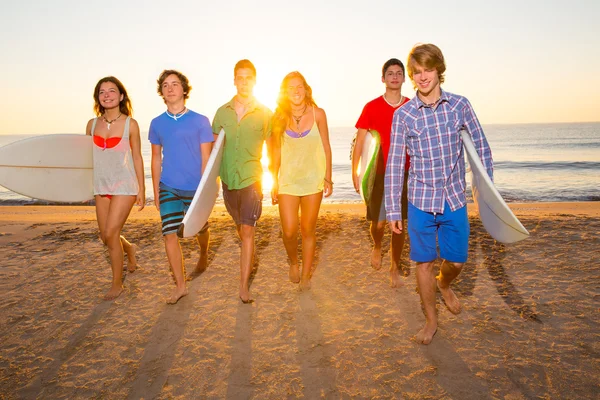 Surfistas grupo de niños y niñas caminando en la playa —  Fotos de Stock