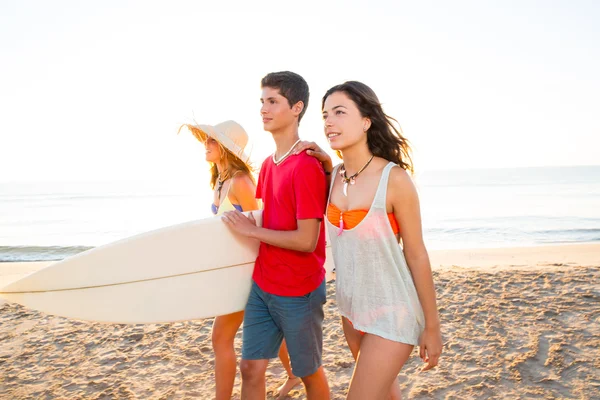 Surfer girls with teen boy walking on beach shore — Stock Photo, Image
