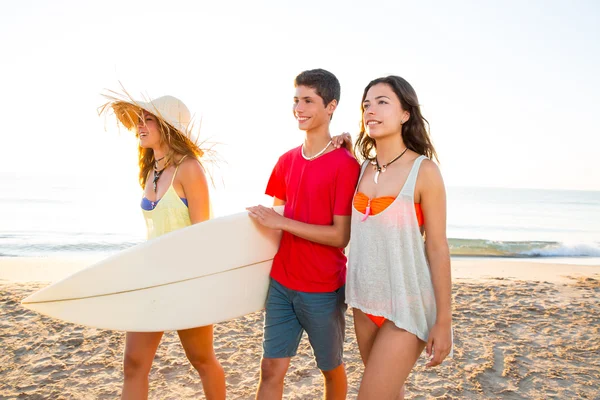 Ragazze surfiste con ragazzo adolescente che cammina sulla spiaggia — Foto Stock