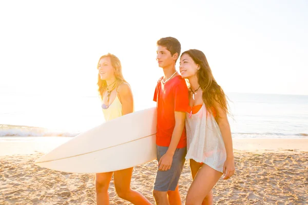 Surfer meisjes met tiener jongen lopen op strand kust — Stockfoto