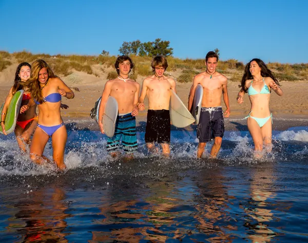 Adolescente surfistas grupo correndo praia espirrando — Fotografia de Stock