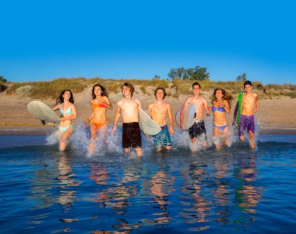 Teenager surfers group running beach splashing — Stock Photo, Image