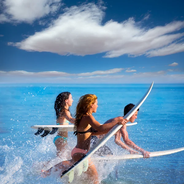 Boys and girls teen surfers running jumping on surfboards — Stock Photo, Image