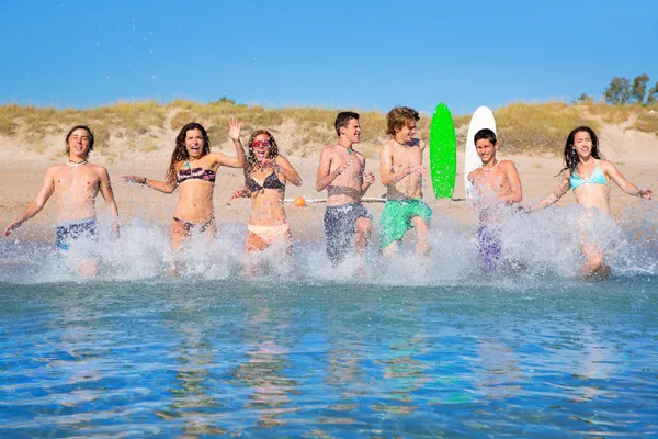 Adolescentes surfistas grupo corriendo playa splashing —  Fotos de Stock