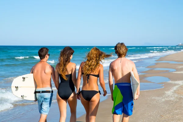 Surfers jongens en meisjes lopen achteraanzicht op strand — Stockfoto