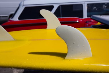 Yellow surfboard keel fins detail eith red retro car in Califor clipart