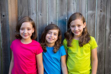 Sister and friends kid girls portrait smiling on gray fence clipart