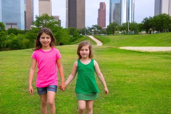 Due ragazze amiche che camminano tenendosi per mano nello skyline urbano — Foto Stock